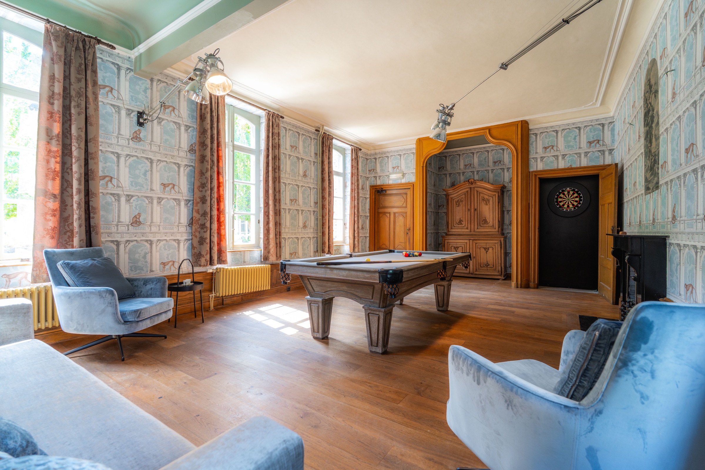 Game room with billiards table, lounge chairs and dartboard at Chateau de Looz