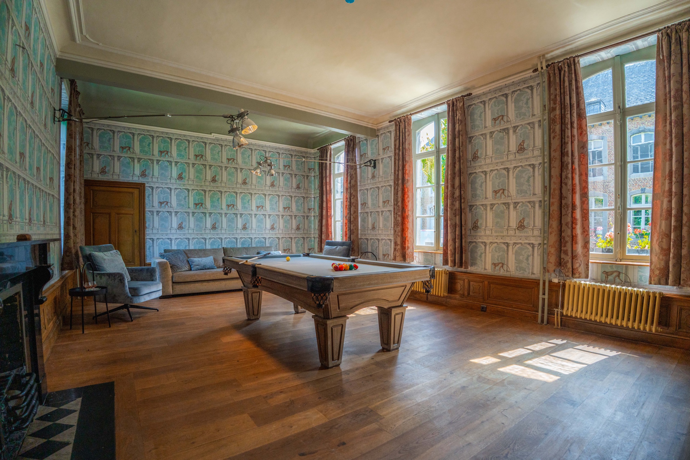 Bright game room with billiards table and historic wallpaper at Chateau de Looz