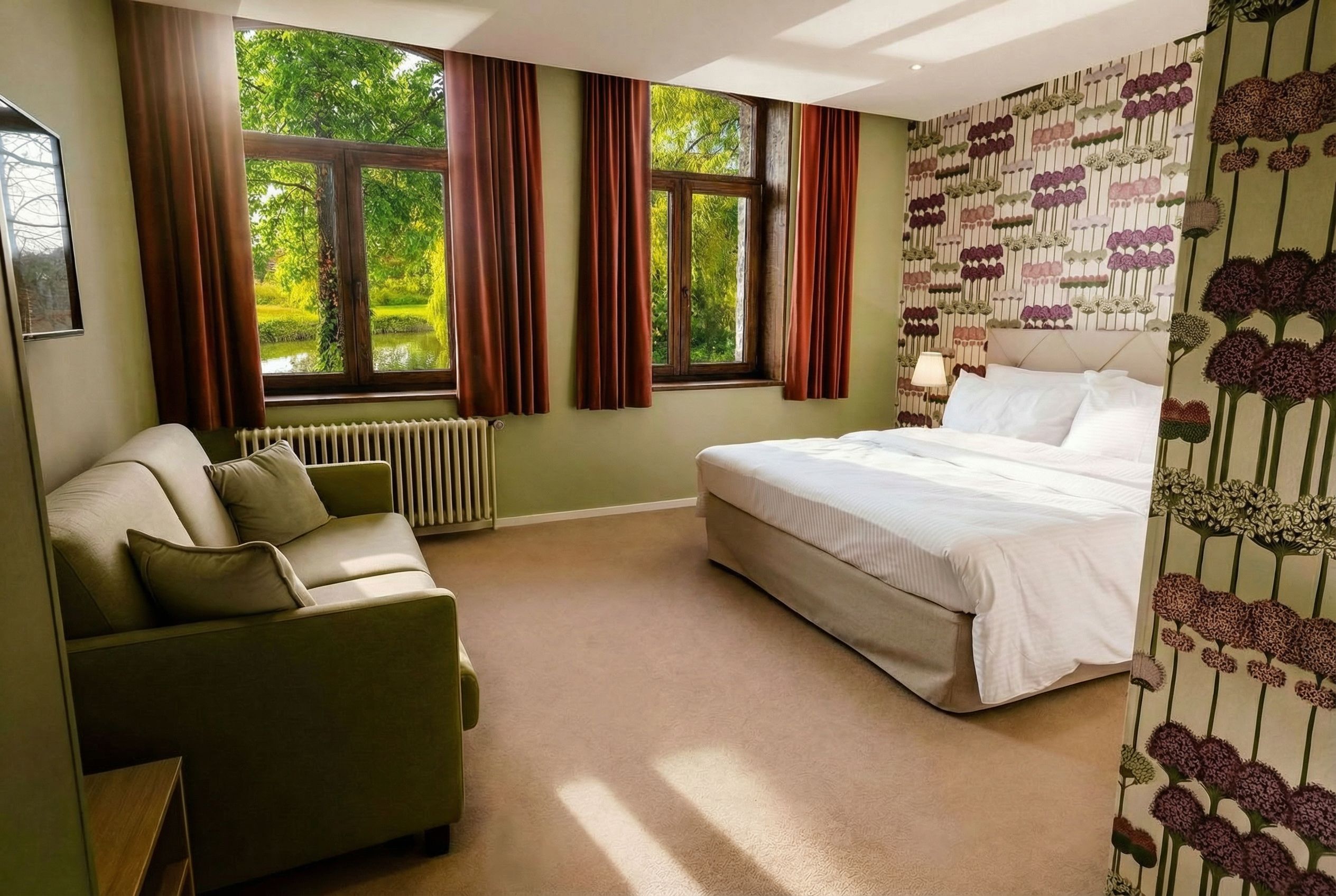 Accessible Junior King Suite with seating area and a view of the water and park at Château de Looz