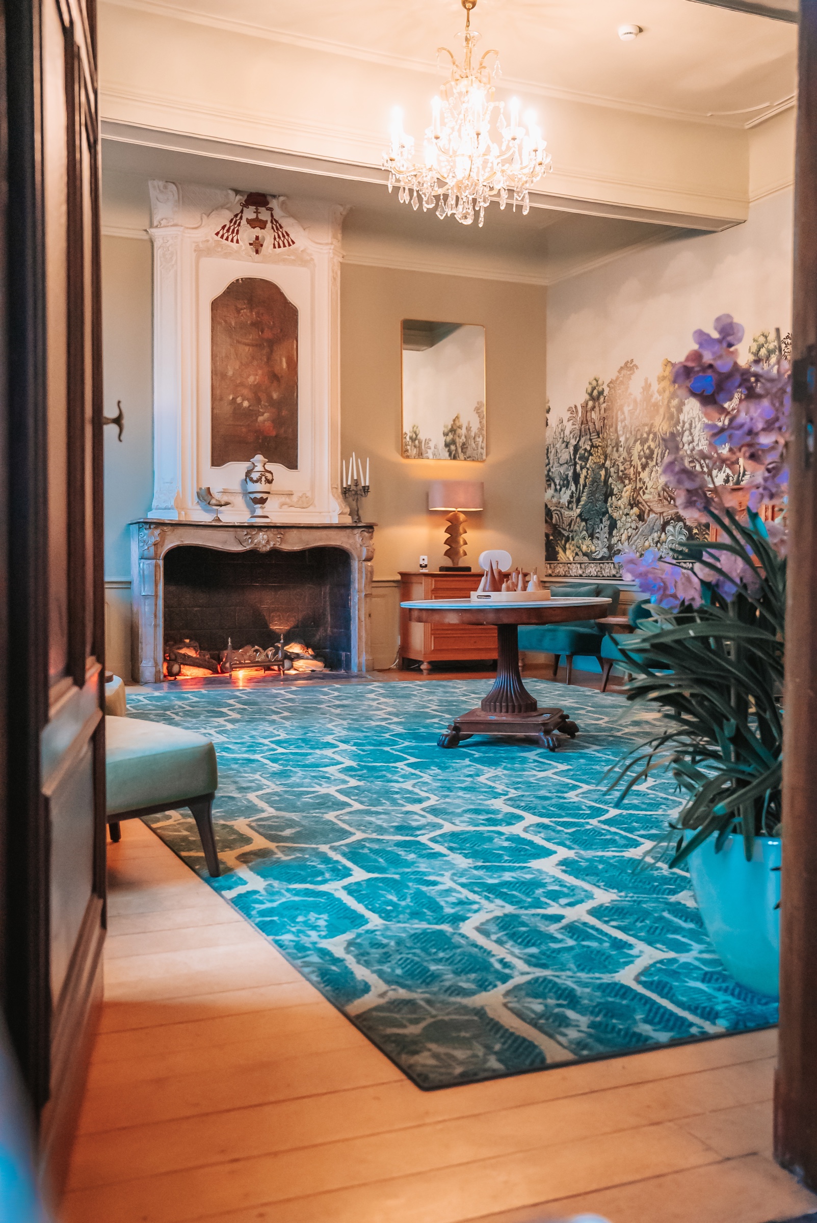 Castle lounge with fireplace, chandelier and soft seating at Château de Looz