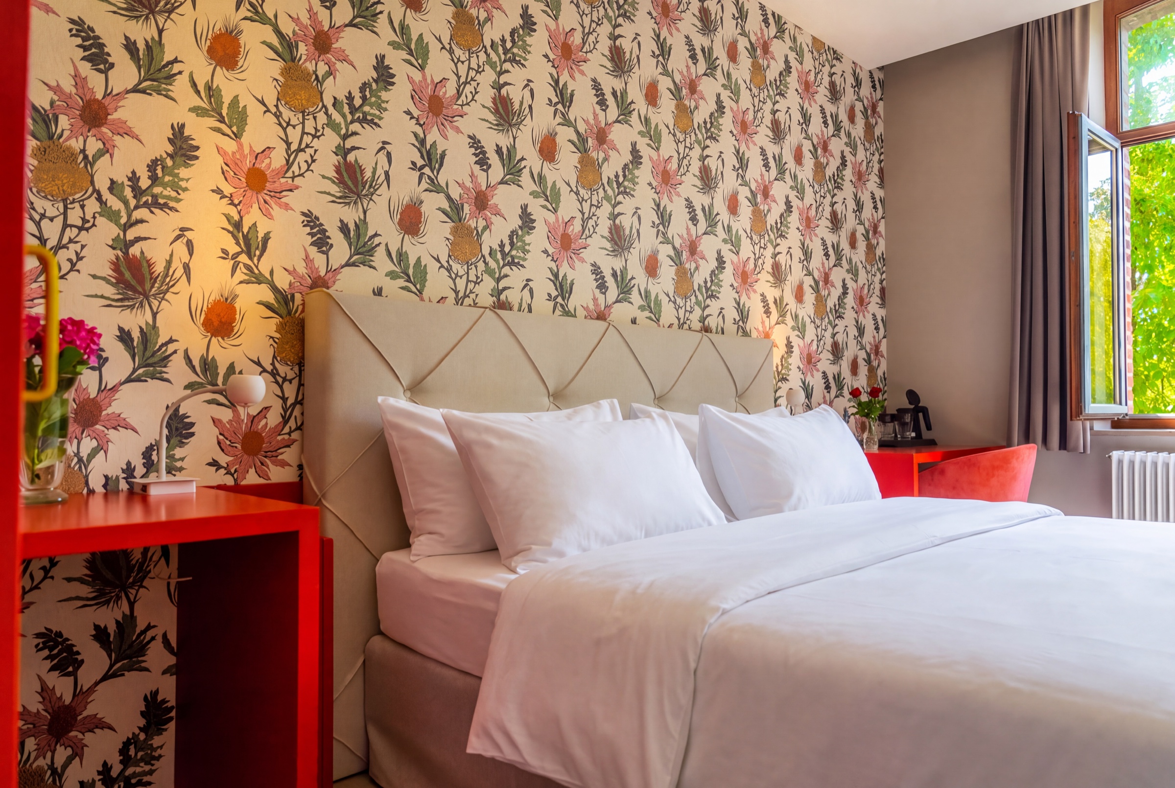 Guest room with botanical wallpaper and warm red details at Château de Looz